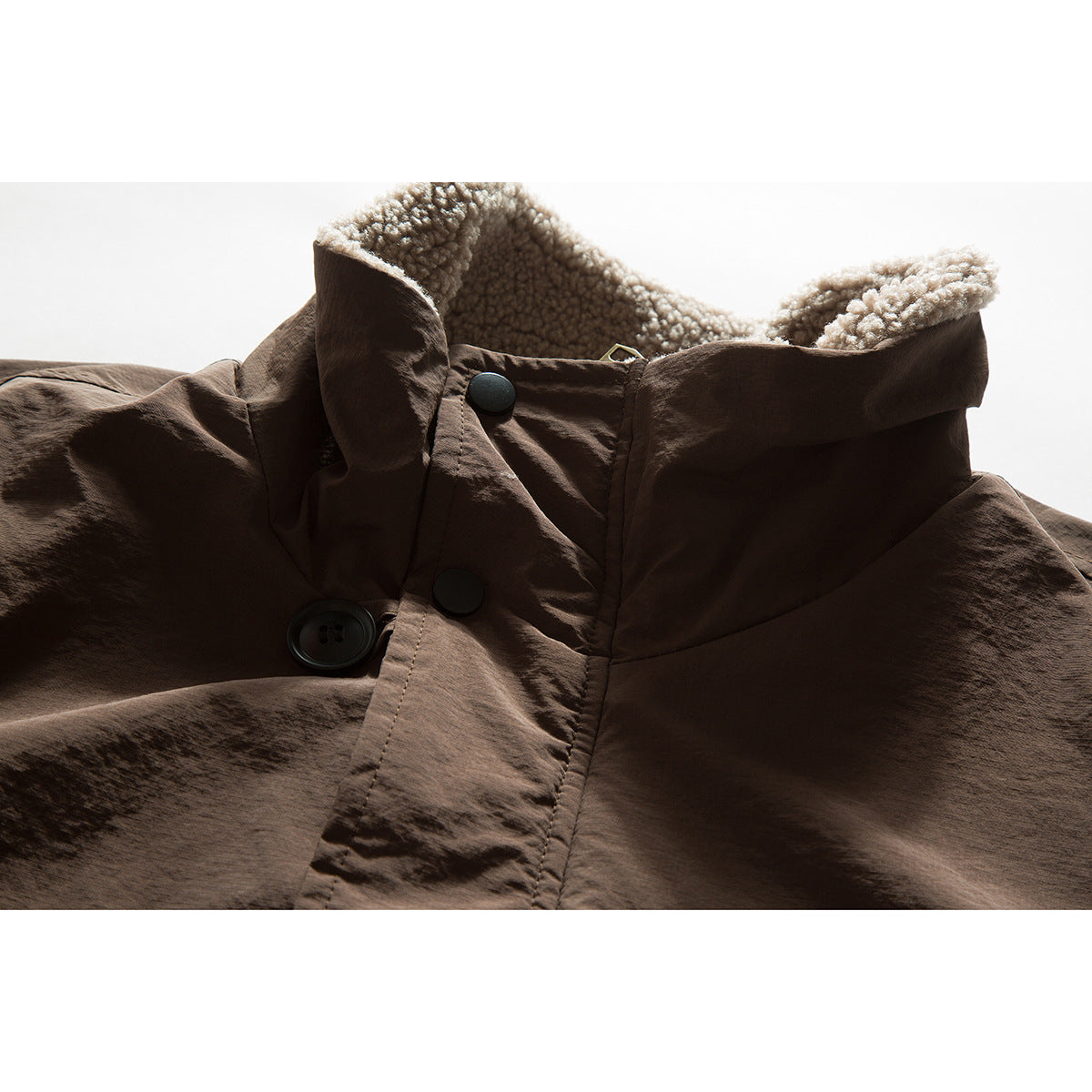 Close-up of a brown jacket's high collar, showing light curly lining and black front buttons.