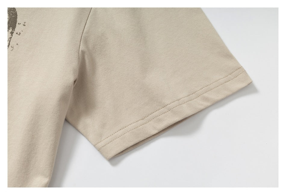 Close-up of the short sleeve and stitched hem on a beige T-shirt.