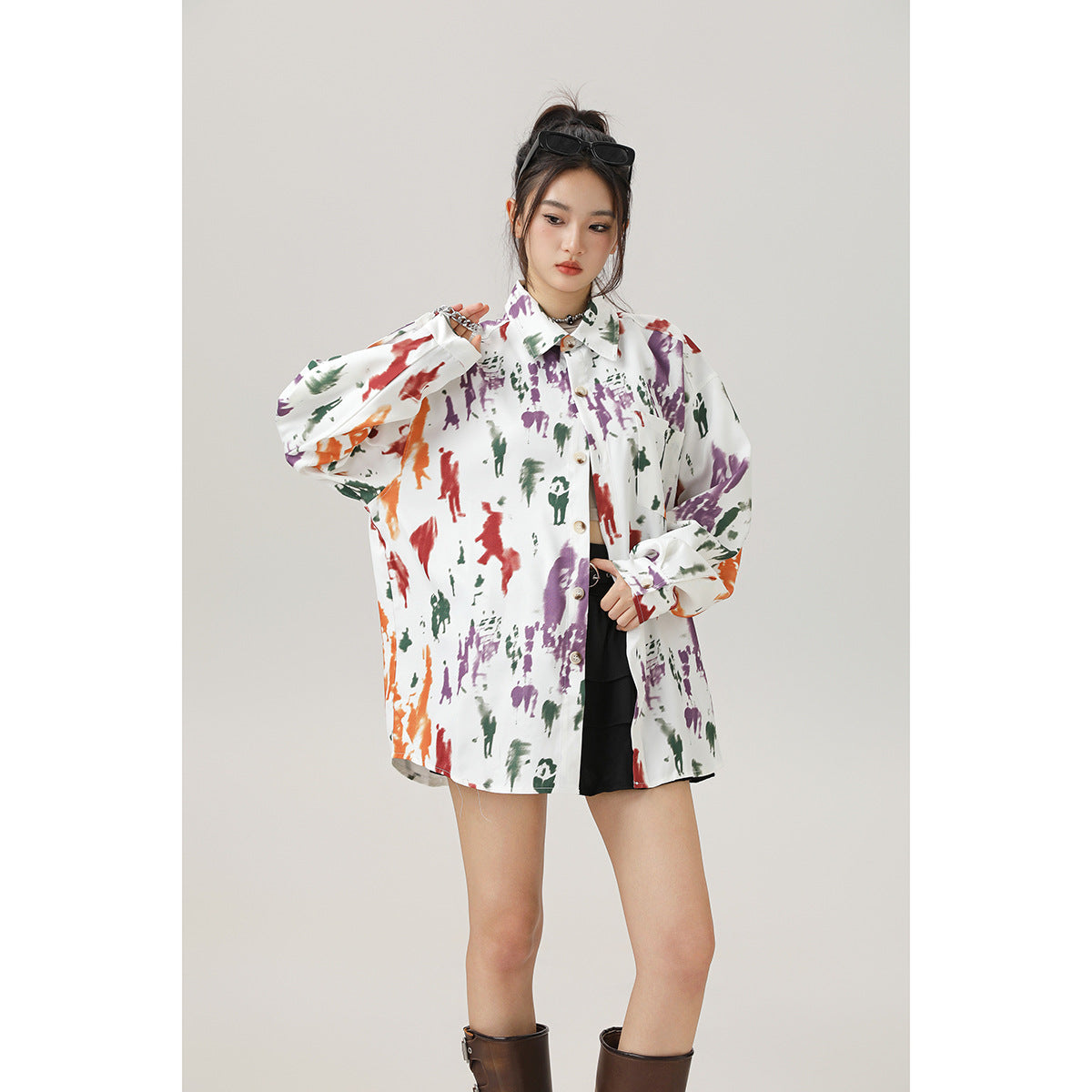 Model wearing an oversized white button-up shirt with colorful abstract prints and long sleeves, shown from the front.