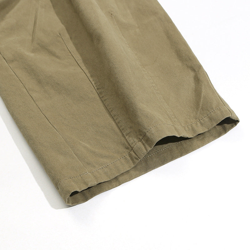 Close-up of the stitched hem and leg opening of khaki trousers.