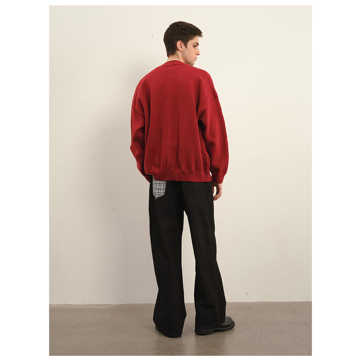 Back view of a model wearing a red cardigan and loose black trousers.