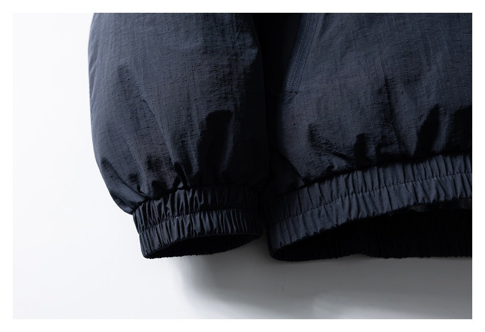Close-up of a dark navy jacket sleeve cuff and elasticated hem with subtle vertical texture.