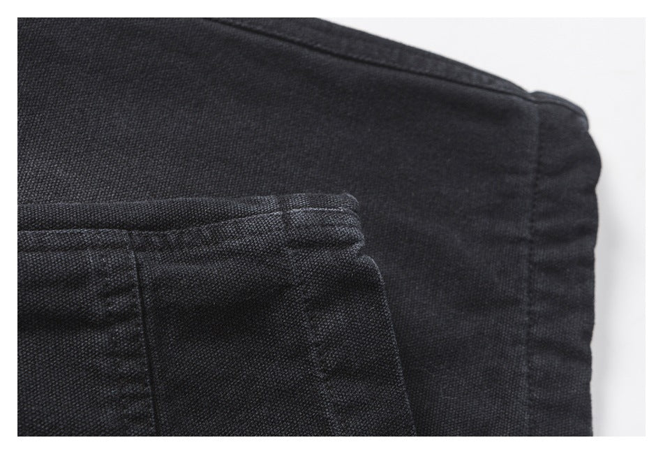 Close-up of black fabric with a stitched seam and folded edge.