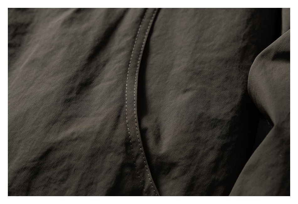 Close-up of a curved stitched seam on dark olive jacket fabric.