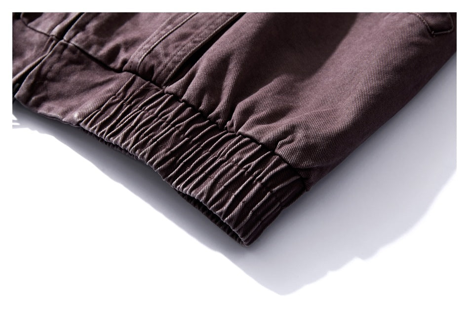 Close-up of the gathered elastic hem on a muted plum-brown jacket.