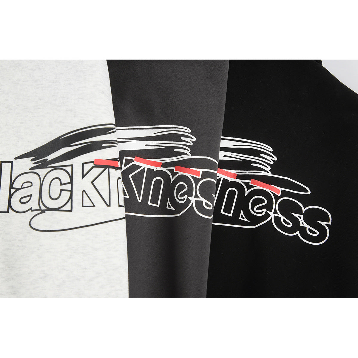 Close-up of a brushstroke and outlined “Blackness” graphic with red accents on three garment colorways.
