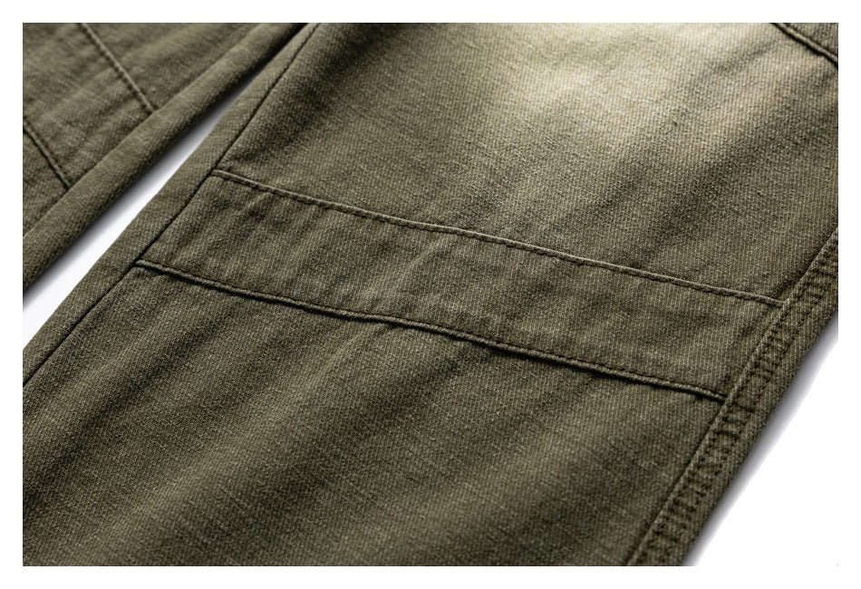 Close-up of olive-brown trousers showing a large stitched patch pocket and seams.
