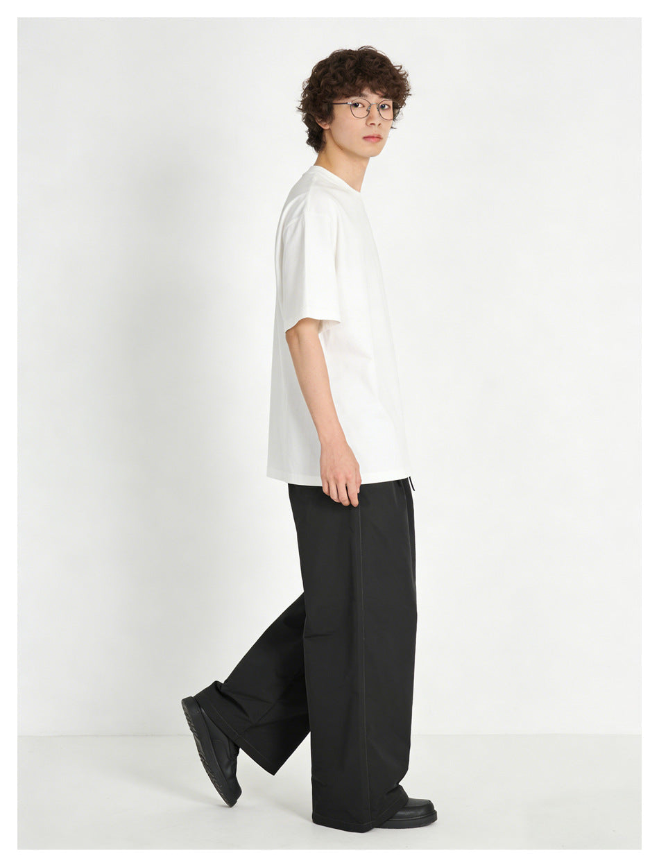 Model in black wide-leg pants and a white tee, side view mid-step