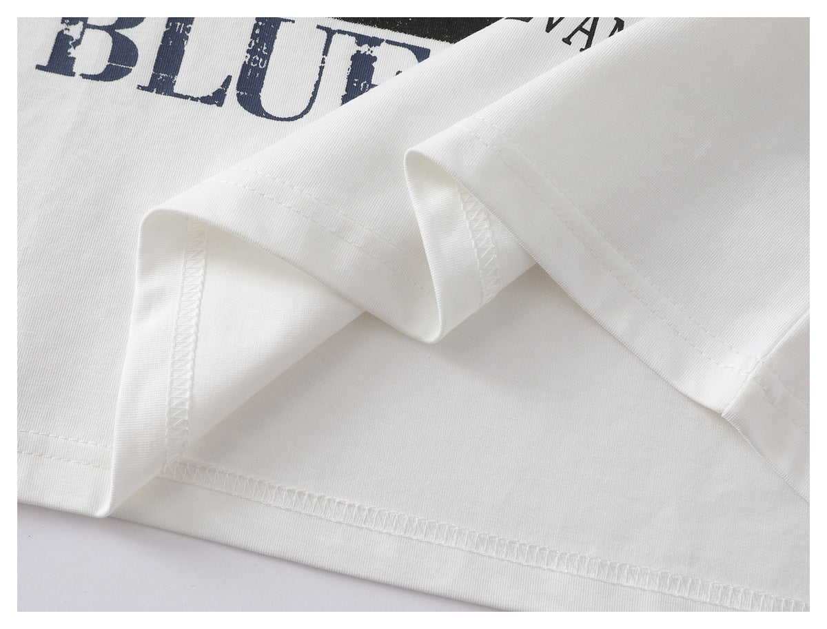 Close-up of the white T-shirt's folded sleeve and stitched hem, with part of its printed graphic visible.