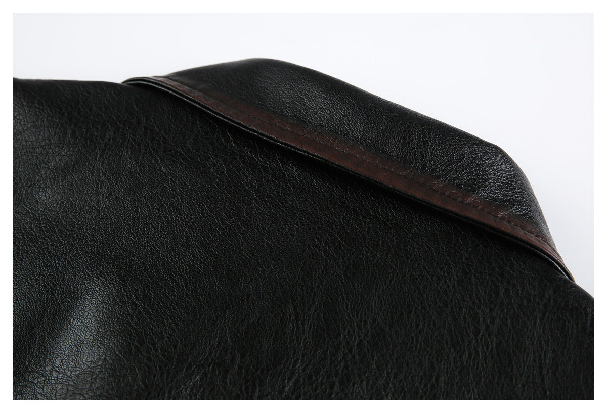 Close-up of a black leather-look jacket collar with dark brown piping along the edge.