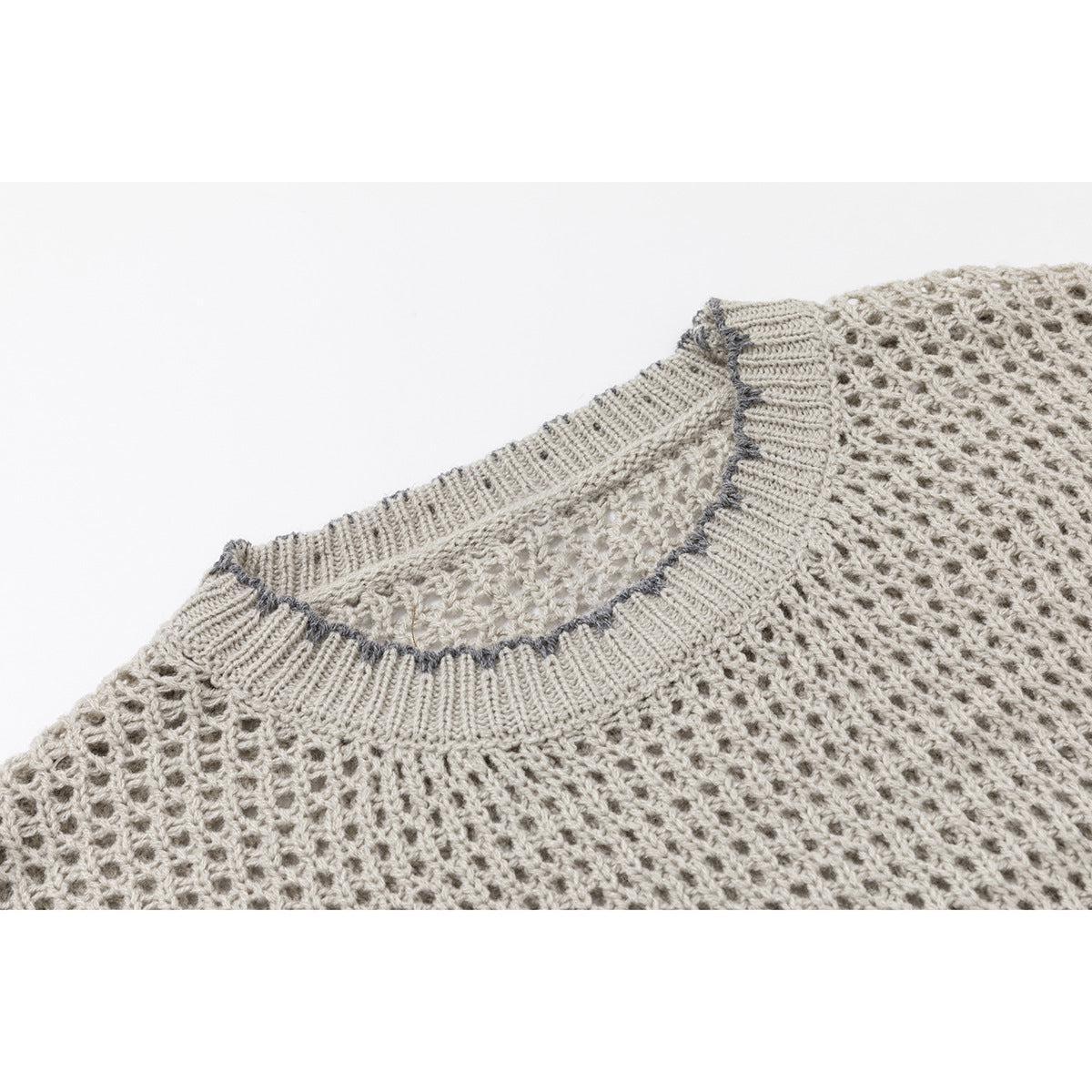 Close-up of a beige open-knit sweater's ribbed crew neckline with dark contrast stitching.