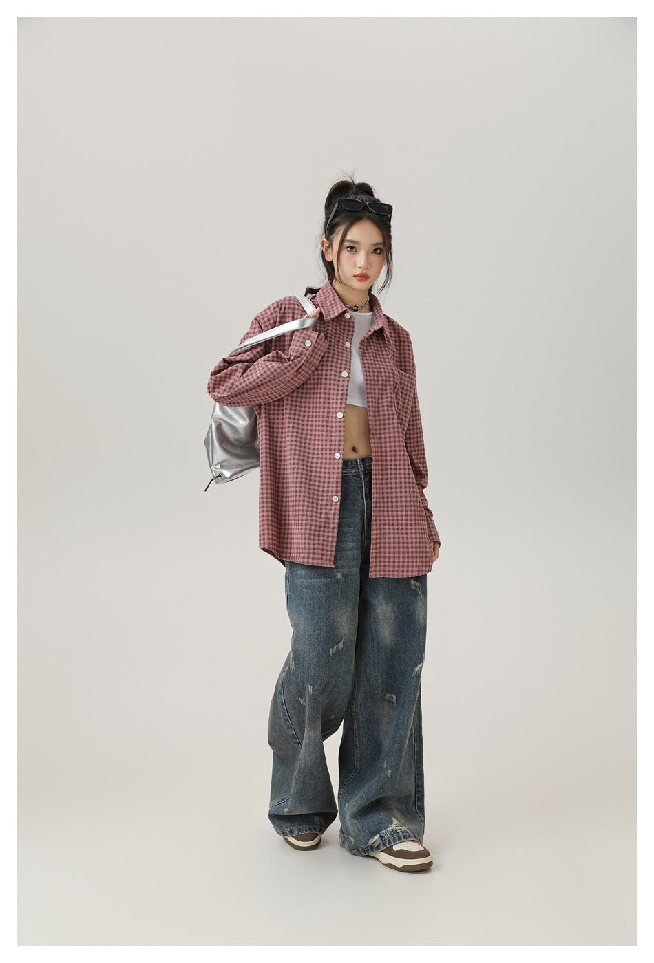 Full-length front view of a model wearing a dusty-pink check shirt and loose distressed jeans.