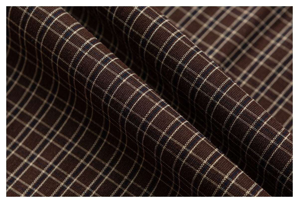 Close-up of folded brown plaid fabric with cream and blue grid lines.