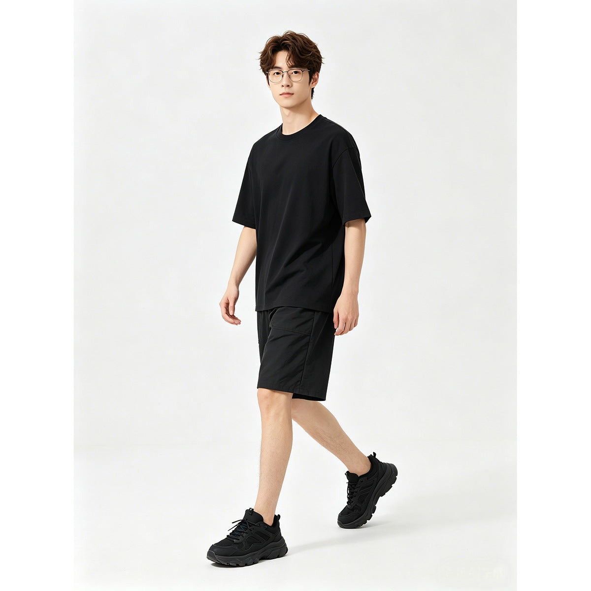 Model wearing a plain black short-sleeve T-shirt with black shorts and black sneakers.