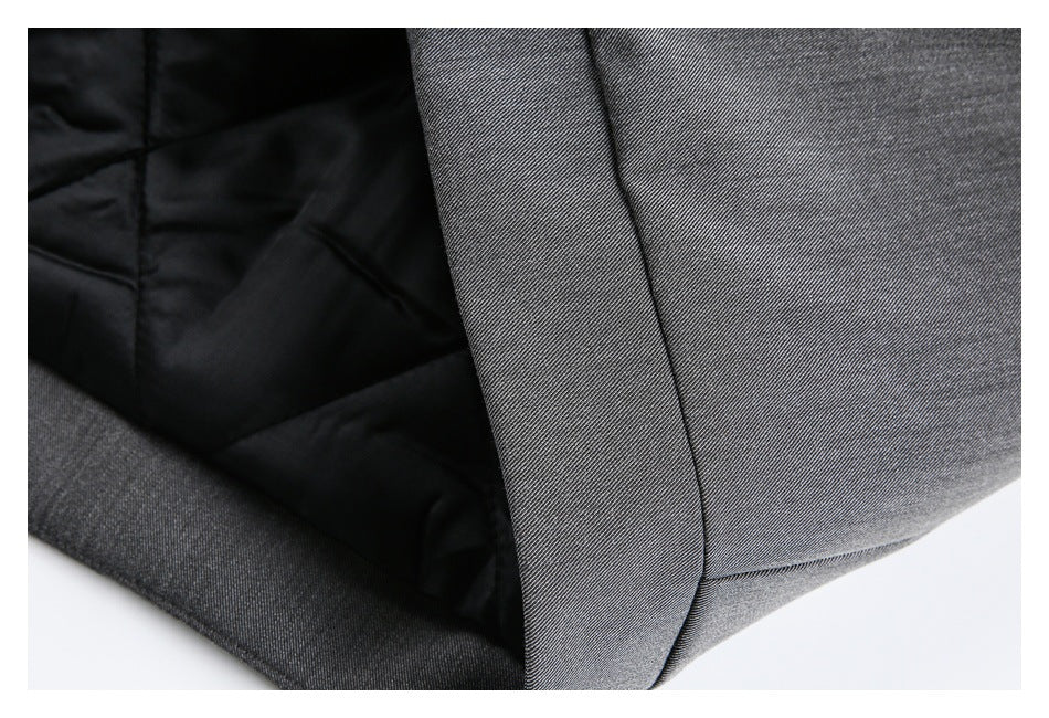 Close-up of charcoal gray garment edge beside black quilted lining and a stitched seam.