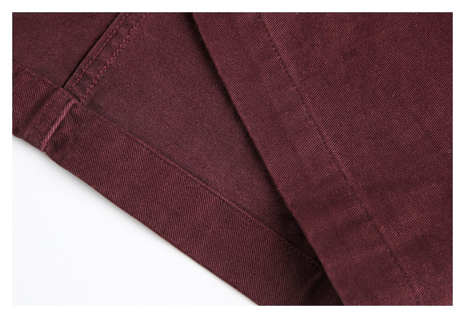 Close-up of burgundy garment fabric showing a folded edge and stitched seams.