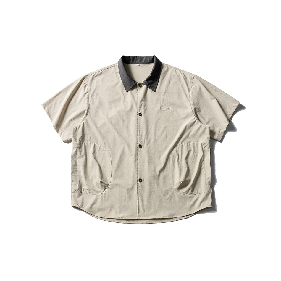 Beige short-sleeve button-up shirt with dark gray collar and two curved side pockets, flat lay front view