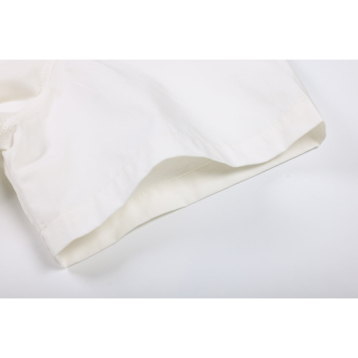 Close-up of the ivory shirt's short-sleeve hem and stitching.