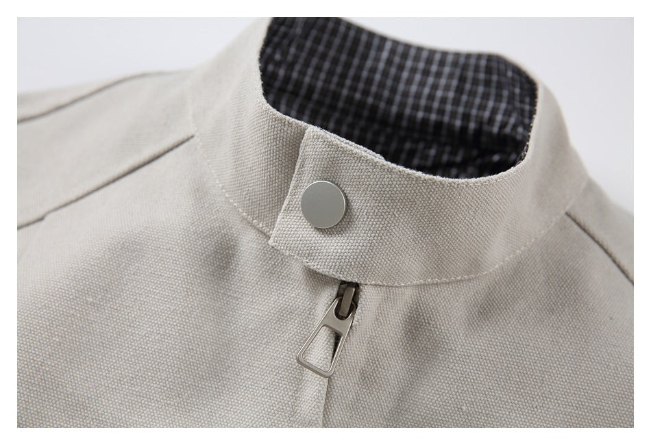 Close-up of a light beige jacket's stand collar, snap closure, front zipper, and checked inner lining.