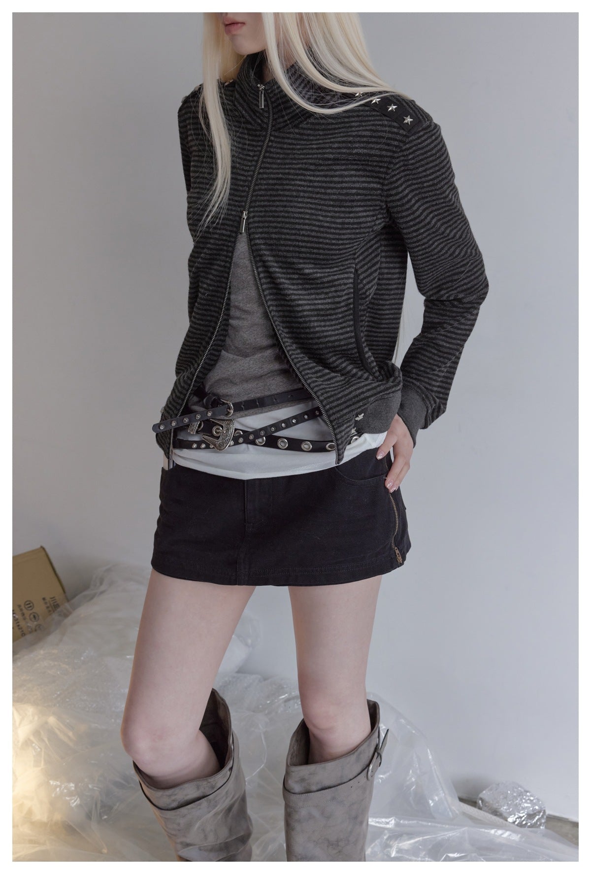 Cropped view of a model wearing an open charcoal striped jacket with star-studded shoulder trim.
