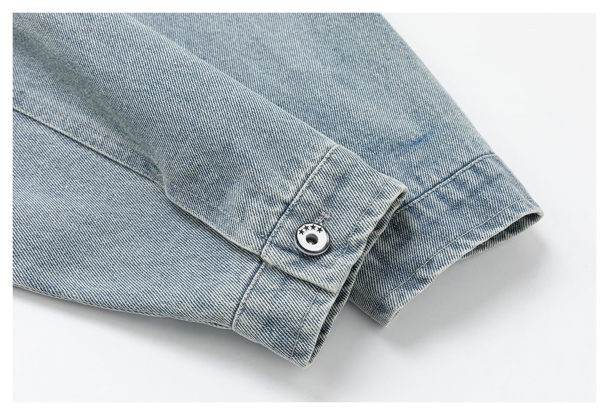 Close-up of a light blue denim cuff with contrast stitching and a round button decorated with stars.
