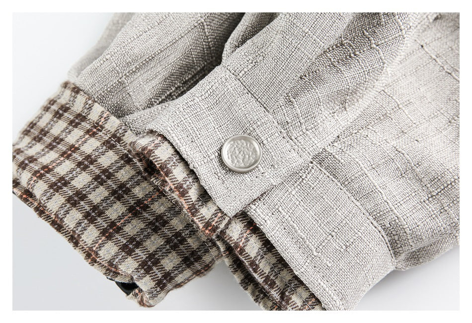 Close-up of a light beige cuff with a white button and brown plaid lining folded back.