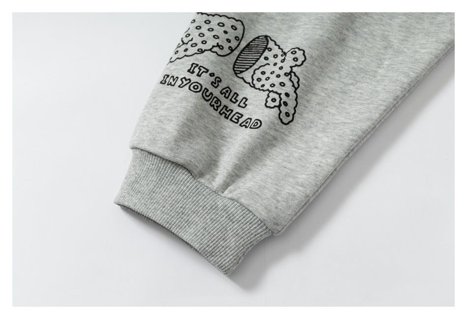 Close-up of a heather gray sweatshirt sleeve with a ribbed cuff and black illustrated print reading “IT'S ALL IN YOUR HEAD.”