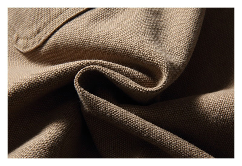 Close-up of taupe-brown woven fabric folded into soft ridges, showing its textured surface.