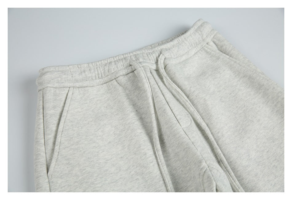 Close-up of light gray marl sweatpants showing the elastic waistband, drawstring, and slanted pocket.