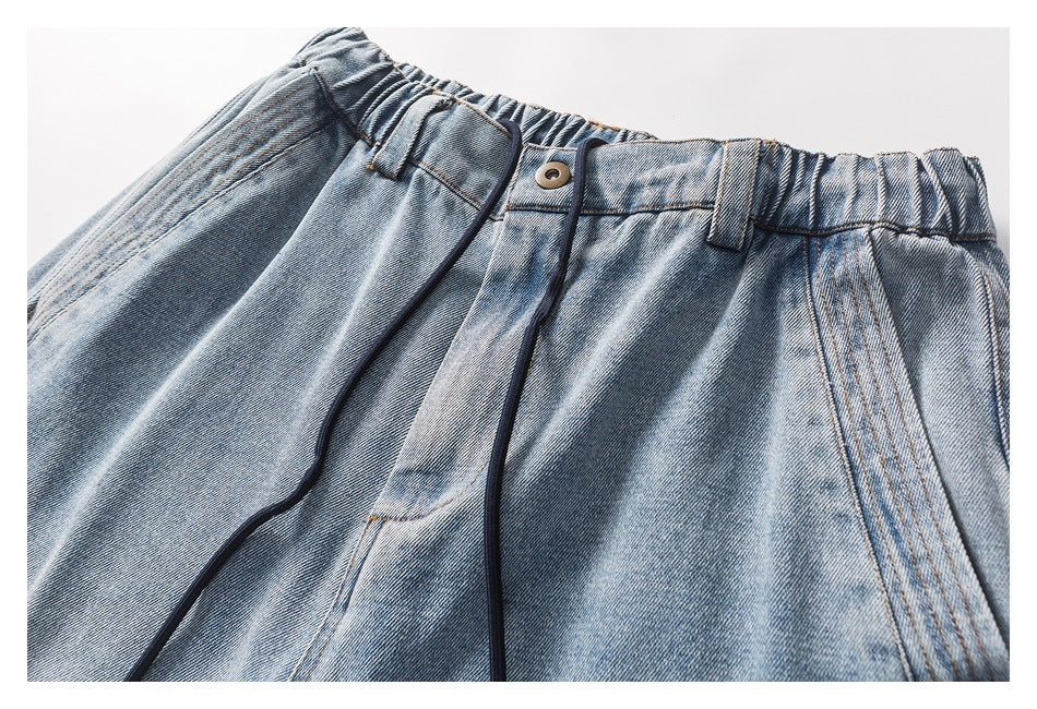 Close-up of the jeans' front waistband, button, belt loops, and dark drawstrings.