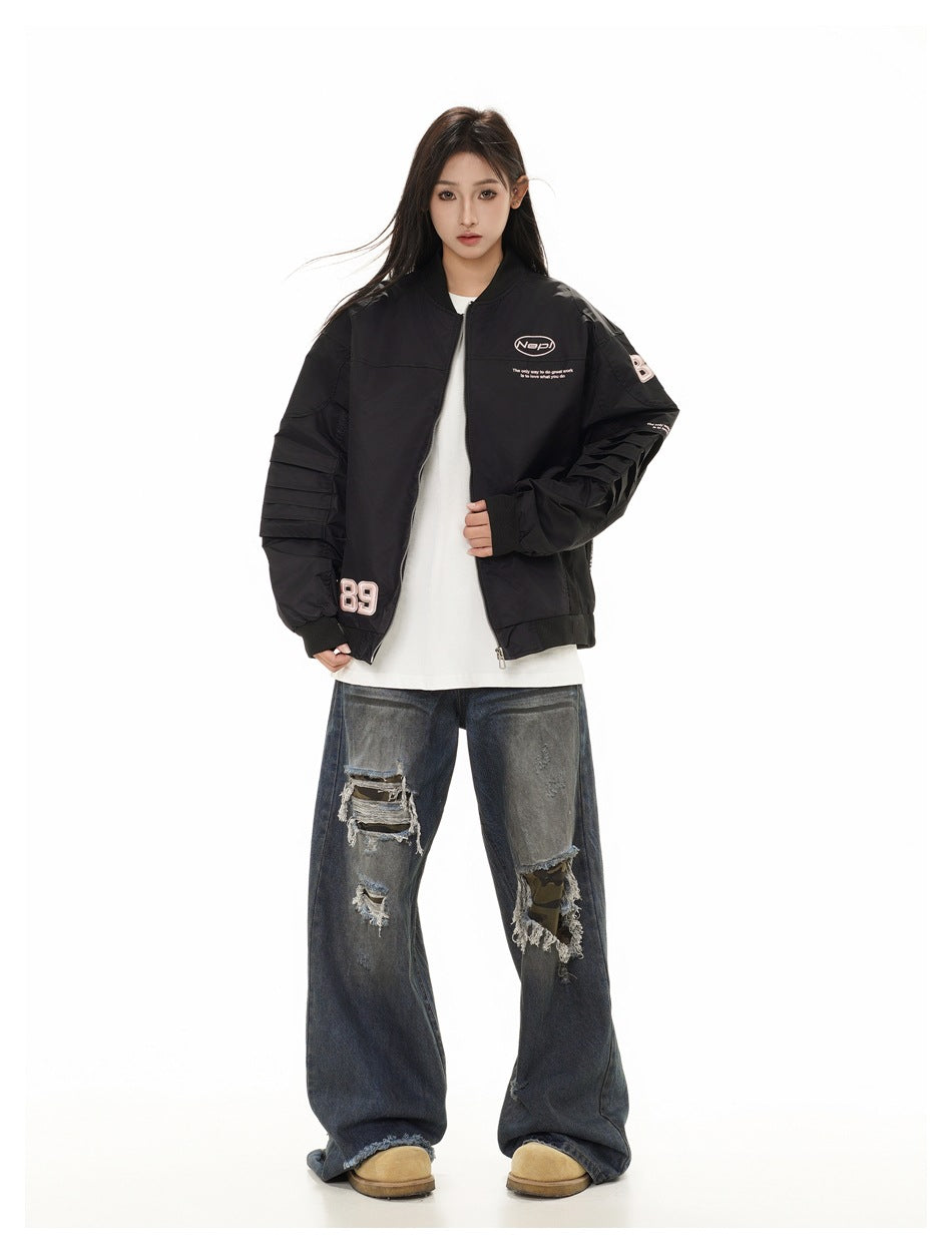 Front view of a model in a black graphic bomber jacket, white shirt, distressed wide-leg jeans and tan shoes.