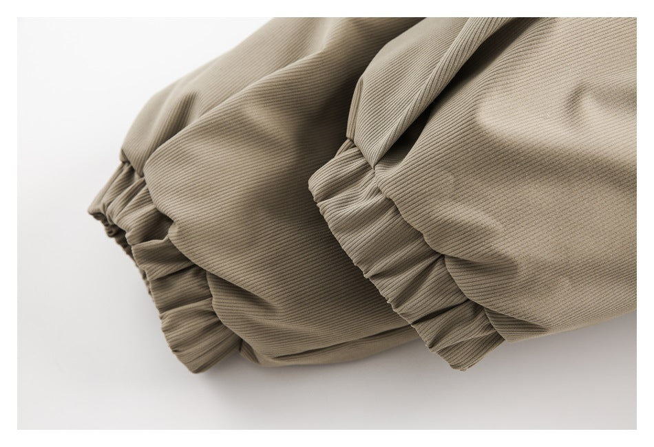 Close-up of gathered, elasticized edges on a taupe ribbed garment.