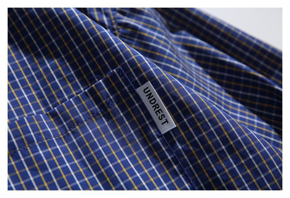 Close-up of the shirt's blue, white, and yellow plaid fabric and sewn UNDREST label.
