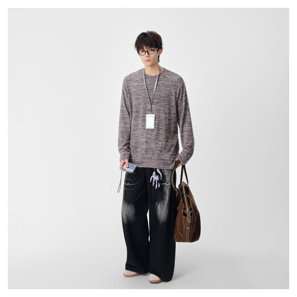 Full-length front view of a model wearing a mottled taupe-gray crewneck sweater and wide black jeans.