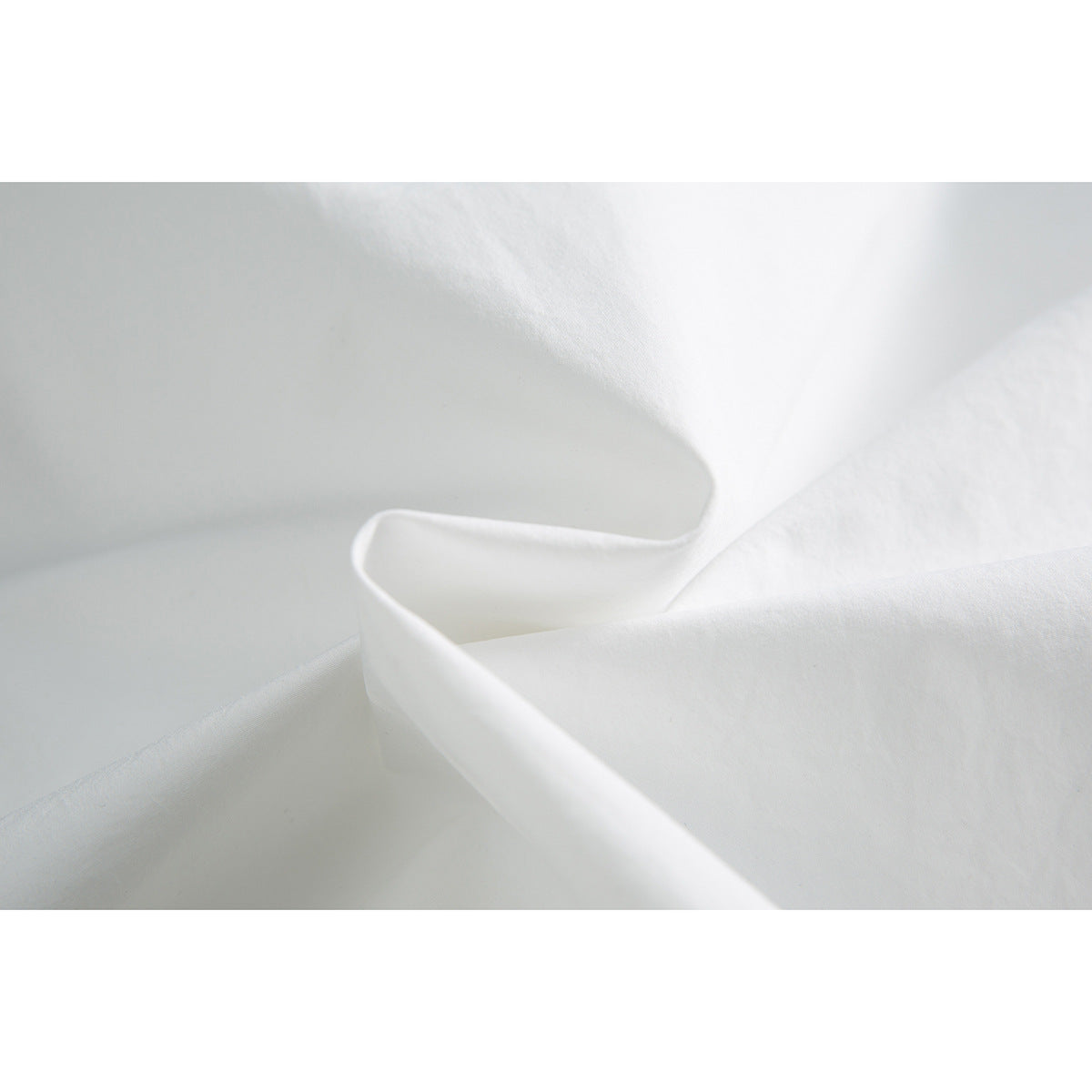 Close-up of folded white fabric showing its smooth surface and edge stitching.