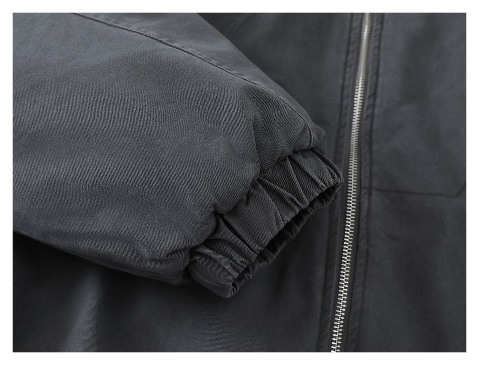 Close-up of a dark charcoal jacket sleeve with a gathered cuff beside a silver front zipper.