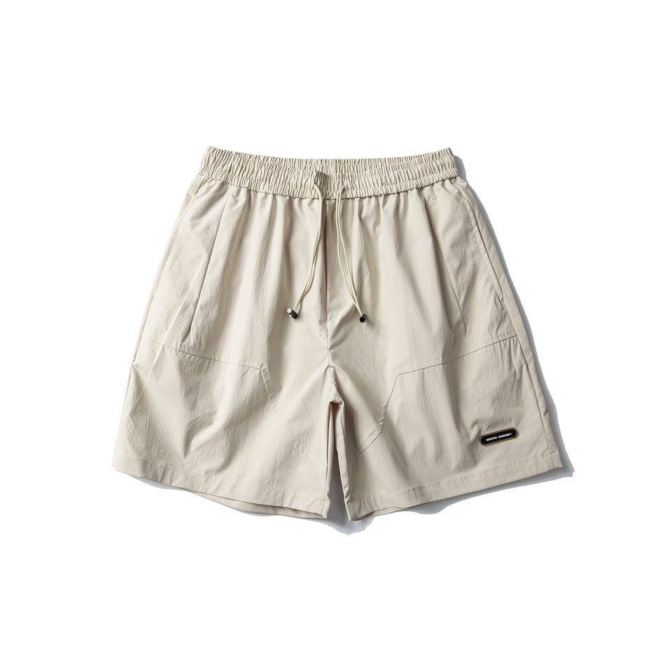 Khaki drawstring shorts with elastic waist, side pockets, curved front seams and a small oval label, flat front view