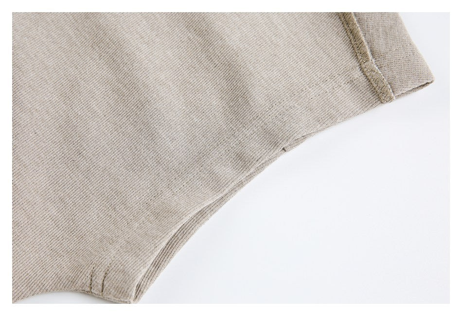 Close-up of taupe knit fabric showing a stitched edge and curved garment seam.
