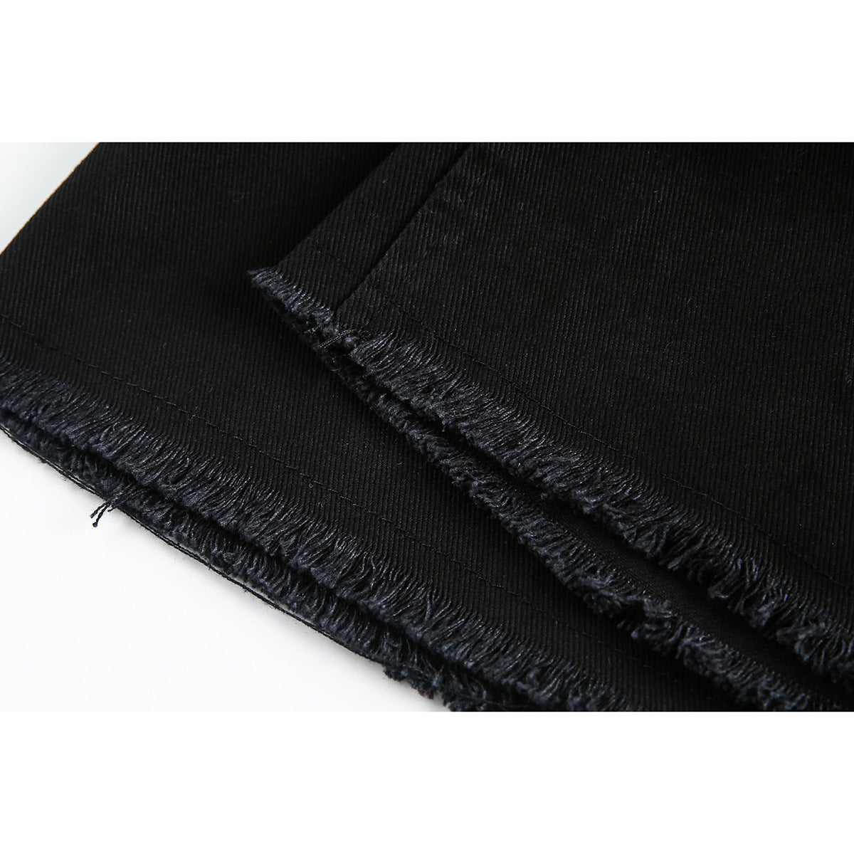 Close-up of the black shorts’ frayed raw hems and stitched seams.