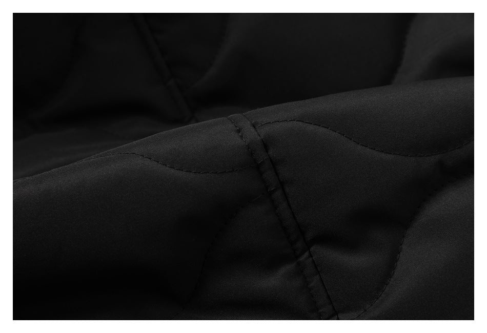 Close-up of black garment fabric showing a curved seam and intersecting stitched panels.