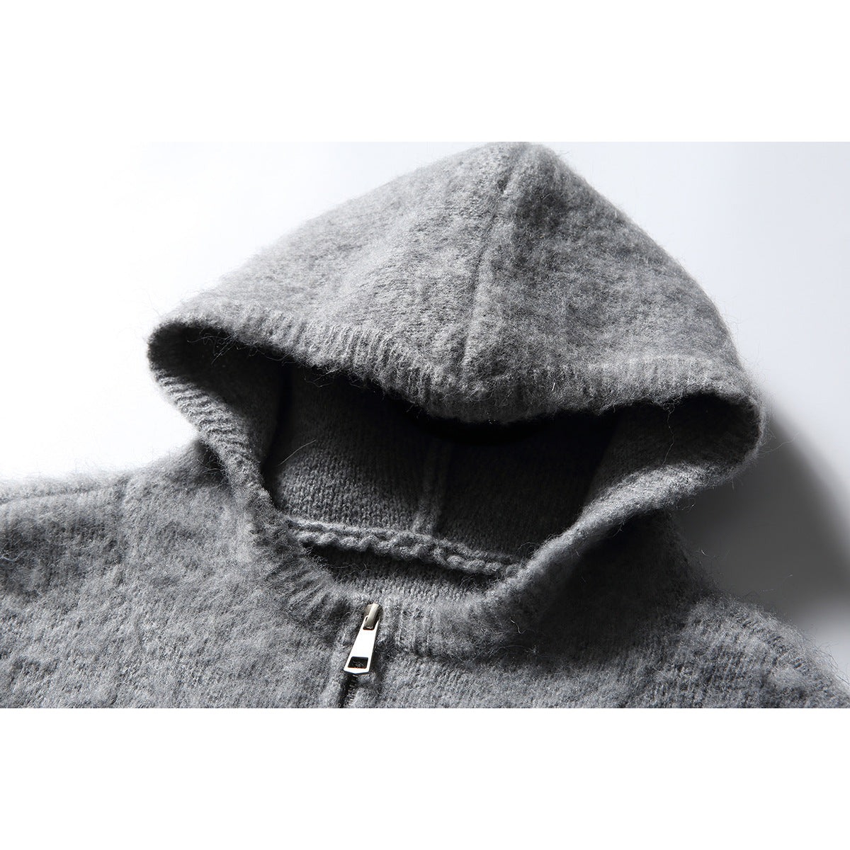 Close-up of the gray knit hood and front zipper on a hooded sweater.