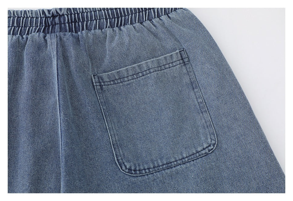Close-up of a rectangular patch pocket on the back of blue denim shorts.