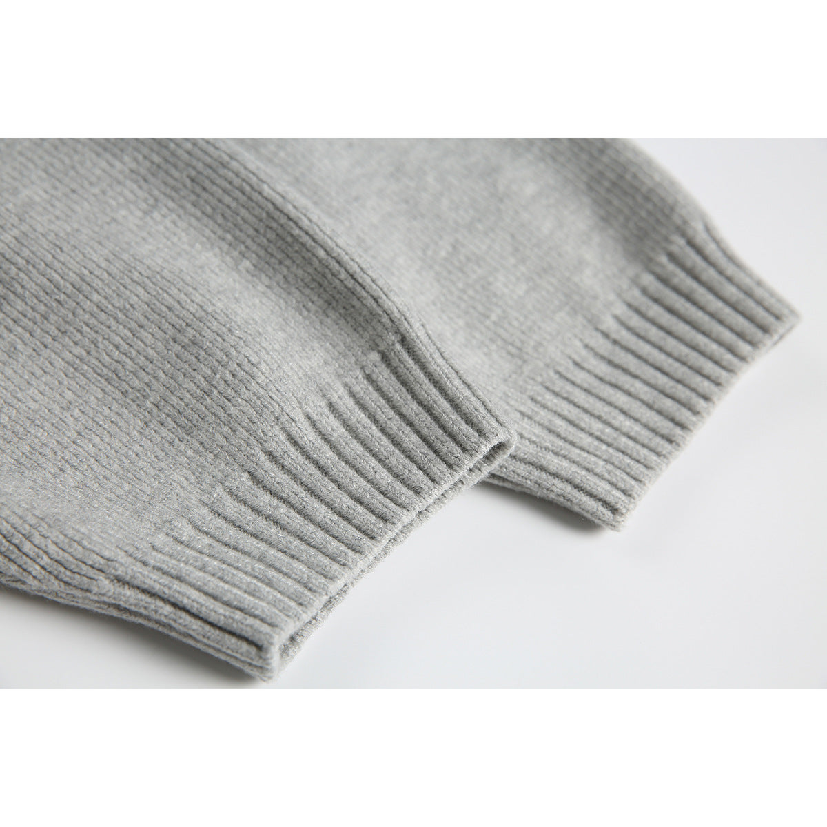 Close-up of the light gray sweater's ribbed sleeve cuffs and hem.