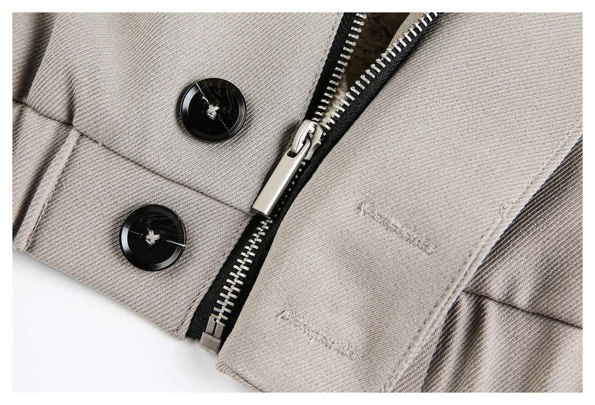 Close-up of a taupe jacket cuff with two black buttons, a silver zipper and small tonal stitching.