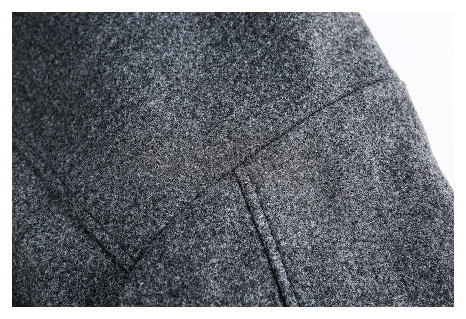 Close-up of a seam and angled pocket detail on the charcoal-gray flecked coat.