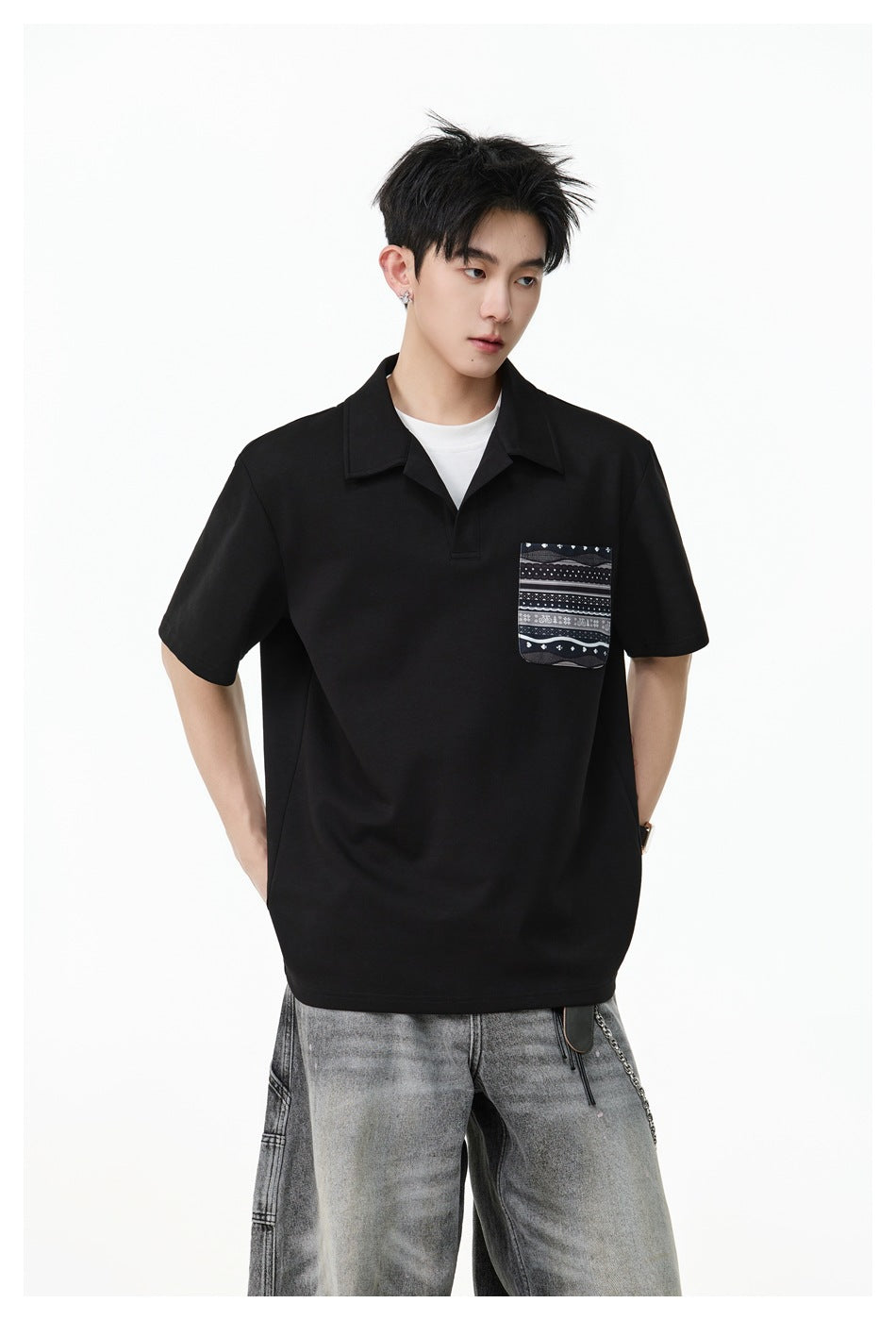 Closer view of a model wearing a black short-sleeve collared polo with a patterned chest pocket.