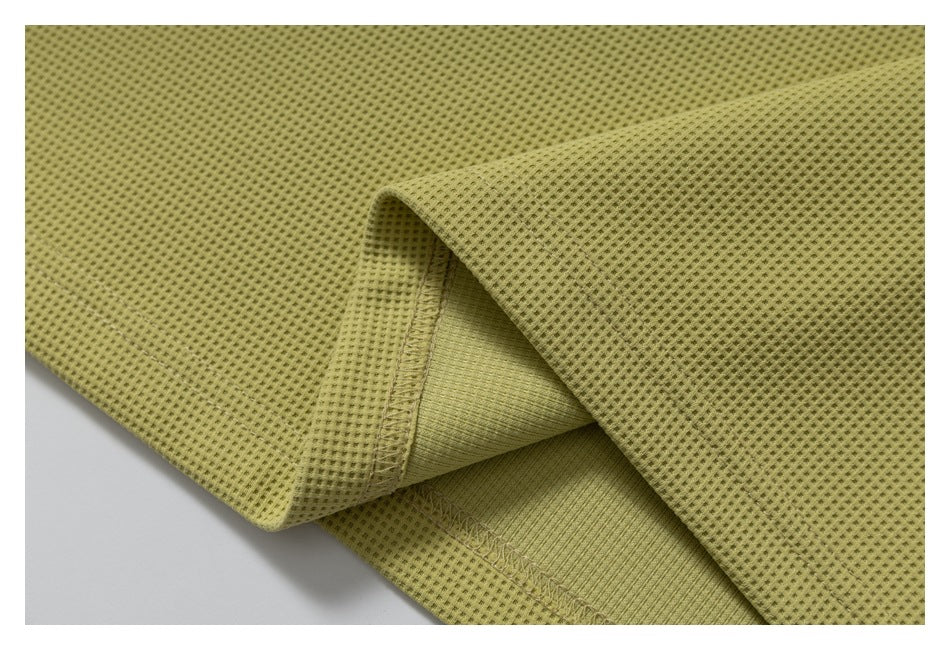 Folded yellow-green waffle-textured fabric showing a stitched seam and smoother inner surface.