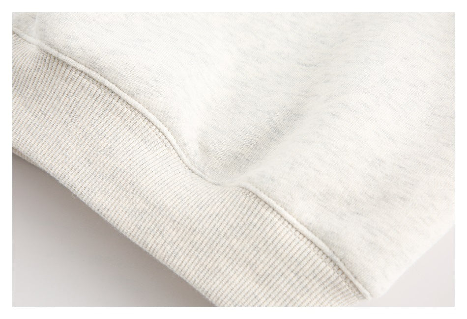 Close-up of the ribbed cuff or hem and seam on an off-white heathered garment.