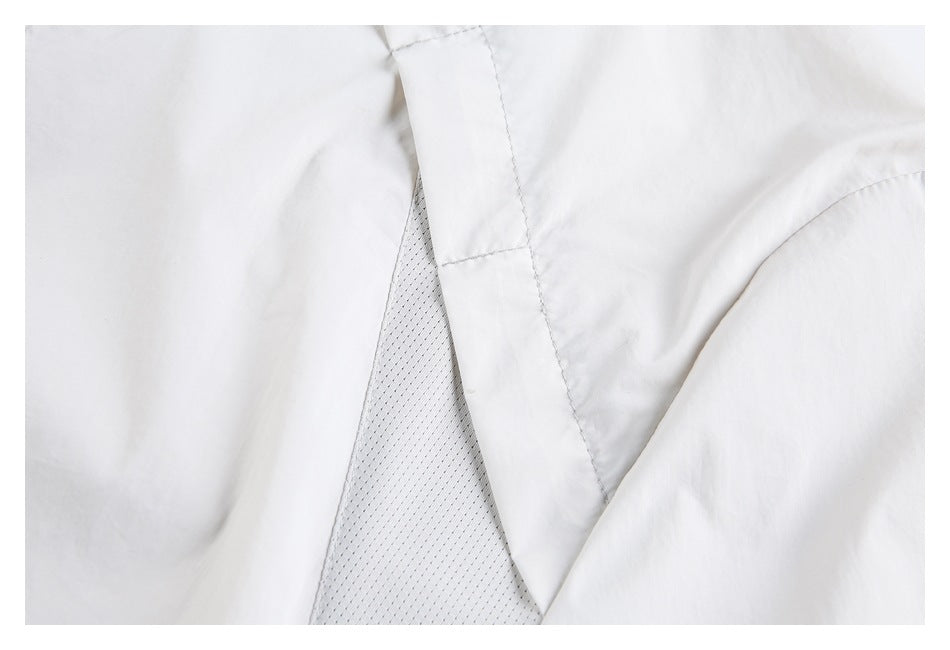 Close-up of a white jacket showing a perforated mesh lining beneath an overlapping fabric panel.