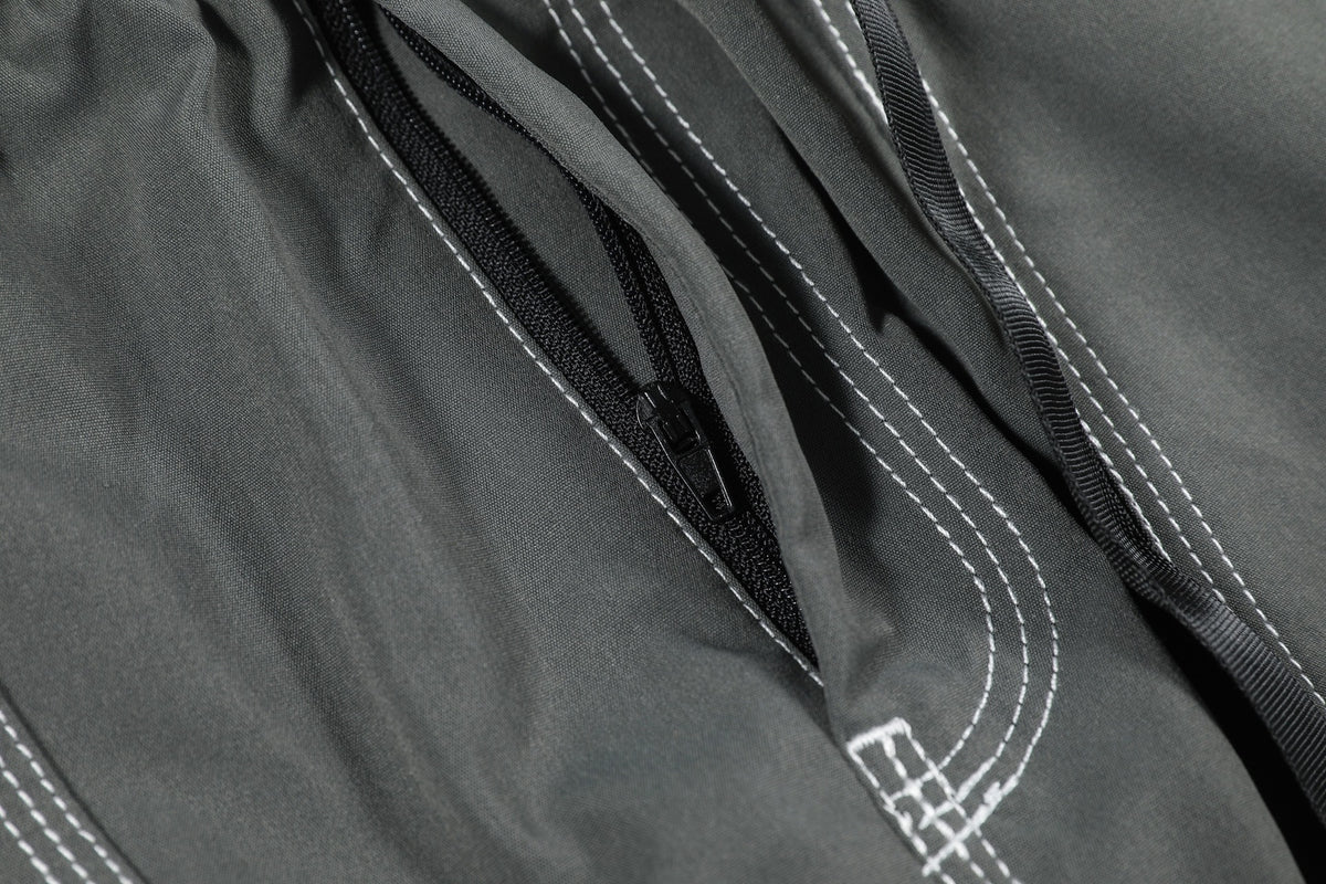 Close-up of charcoal gray garment fabric with a black zipper and contrasting white stitching.